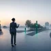 Geschäftsfrau an einer Wegkreuzung auf einem urbanen Platz, drei Lichtpfeiler in verschiedenen Höhen symbolisieren Tarifstufen.