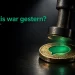 Eine goldene Münze fällt auf eine Fläche und wird von einem Stempel mit einer leuchtenden Sprechblasenform getroffen.
